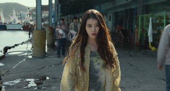 Movie still from “Broker” (2022), directed by Kore-eda Hirokazu – A young woman walking down the street in a yellow jacket; Medium shot, Over the shoulder angle