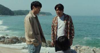 Movie still from “Broker” (2022), directed by Kore-eda Hirokazu – Two men standing on the beach looking at each other; Medium shot, Over the shoulder angle