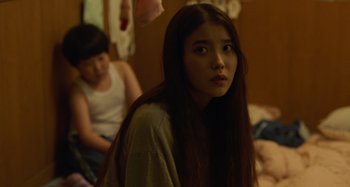 Movie still from “Broker” (2022), directed by Kore-eda Hirokazu – Two young women sitting on a bed in a room; Close Up shot, Over the shoulder angle