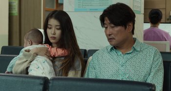 Movie still from “Broker” (2022), directed by Kore-eda Hirokazu – A man and a woman sitting next to each other on a train; Medium shot, Over the shoulder angle