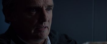Movie still from “Speed” (1994), directed by Jan de Bont – An older man looking at the camera in a dark room; Close Up shot, Low angle