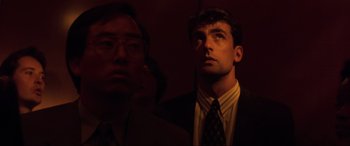 Movie still from “Speed” (1994), directed by Jan de Bont – A man standing next to another man in a suit; Close Up shot, Low angle