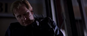 Movie still from “Speed” (1994), directed by Jan de Bont – A man in a black jacket with a microphone in his ear; Close Up shot, Low angle