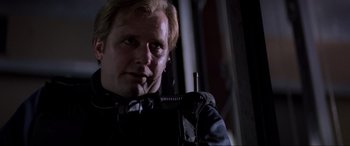Movie still from “Speed” (1994), directed by Jan de Bont – A man in a black jacket is talking on the phone; Close Up shot, Low angle
