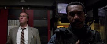 Movie still from “Speed” (1994), directed by Jan de Bont – A man in a black jacket standing next to another man in a white jacket; Close Up shot, Low angle