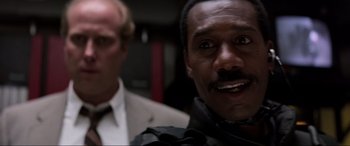 Movie still from “Speed” (1994), directed by Jan de Bont – A man in a suit standing next to another man in a suit; Close Up shot, Low angle