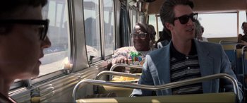 Movie still from “Speed” (1994), directed by Jan de Bont – A man sitting on a bus next to another man; Medium shot, Over the shoulder angle