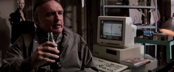 Movie still from “Speed” (1994), directed by Jan de Bont – An older man sitting in front of a computer; Close Up shot, Low angle