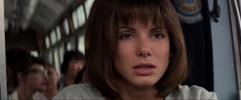 Movie still from “Speed” (1994), directed by Jan de Bont – A person with short brown hair; Close Up shot, Over the shoulder angle