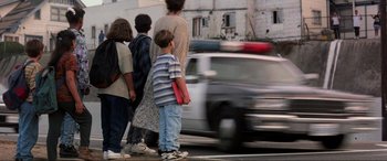 Movie still from “Speed” (1994), directed by Jan de Bont – A group of people standing next to each other on the side of the road; Wide shot, Low angle