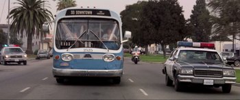 Movie still from “Speed” (1994), directed by Jan de Bont – A bus driving down a street next to a police car; Wide shot, Low angle