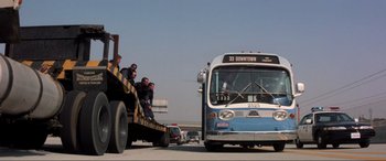 Movie still from “Speed” (1994), directed by Jan de Bont – People are sitting on the back of a bus on the road; Wide shot, Low angle