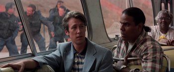 Movie still from “Speed” (1994), directed by Jan de Bont – A man sitting on a bus next to another man; Medium shot, Over the shoulder angle
