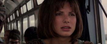 Movie still from “Speed” (1994), directed by Jan de Bont – A person with short brown hair; Close Up shot, Over the shoulder angle