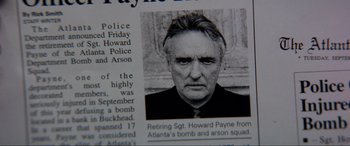 Movie still from “Speed” (1994), directed by Jan de Bont – A newspaper article with an image of an older man; Close Up shot, High angle