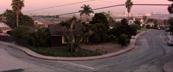 Movie still from “Speed” (1994), directed by Jan de Bont – A view of a street corner with palm trees and a house in the background; Extreme Wide shot, High angle