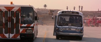 Movie still from “Speed” (1994), directed by Jan de Bont – Two buses driving down a road near a palm tree; Wide shot, Low angle