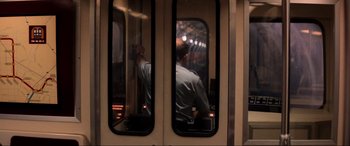 Movie still from “Speed” (1994), directed by Jan de Bont – A man sitting on a train looking out of a window; Wide shot, Over the shoulder angle