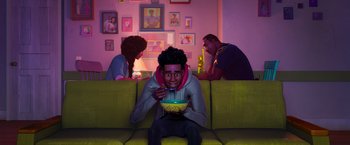 Movie still from “Spider-Man: Across the Spider-Verse” (2023), directed by Joaquim Dos Santos – A man sitting on top of a green couch; Medium shot, Over the shoulder angle