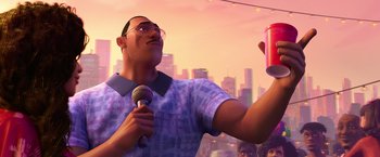 Movie still from “Spider-Man: Across the Spider-Verse” (2023), directed by Joaquim Dos Santos – A man holding a microphone in front of a cell phone; Medium shot, Low angle