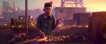 Movie still from “Spider-Man: Across the Spider-Verse” (2023), directed by Joaquim Dos Santos – A man with headphones on standing next to a table with a mixer; Medium shot, Low angle