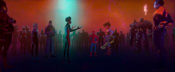 Movie still from “Spider-Man: Across the Spider-Verse” (2023), directed by Joaquim Dos Santos – A group of people standing in front of each other in a room; Wide shot, Over the shoulder angle