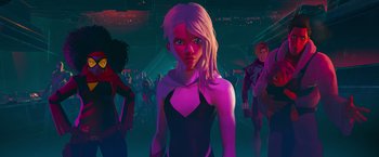 Movie still from “Spider-Man: Across the Spider-Verse” (2023), directed by Joaquim Dos Santos – A woman standing in front of a group of people in a dark room; Medium shot, Low angle