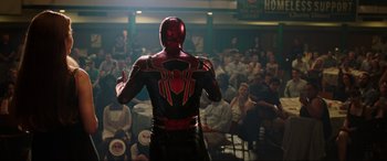 Movie still from “Spider-Man: Far from Home” (2019), directed by Jon Watts – A man in a red and black costume standing in front of a crowd; Medium shot, Over the shoulder angle