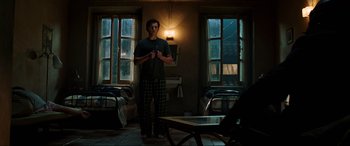 Movie still from “Spider-Man: Far from Home” (2019), directed by Jon Watts – A man standing in a living room holding a remote; Wide shot, Low angle