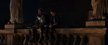 Movie still from “Spider-Man: Far from Home” (2019), directed by Jon Watts – Two men sitting on a bench looking at their cell phones; Wide shot, Over the shoulder angle