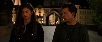 Movie still from “Spider-Man: Far from Home” (2019), directed by Jon Watts – A man and a woman standing next to each other in front of an archway at night; Close Up shot, Over the shoulder angle