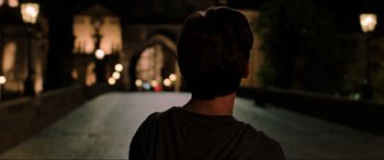 Movie still from “Spider-Man: Far from Home” (2019), directed by Jon Watts – A man standing on a street at night with lights in the background; Medium shot, Over the shoulder angle