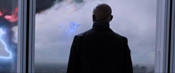 Movie still from “Spider-Man: Far from Home” (2019), directed by Jon Watts – A bald man is looking out a window at the sky; Medium shot, Over the shoulder angle