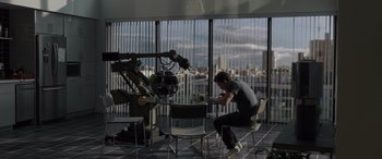 Movie still from “Spider-Man: No Way Home” (2021), directed by Jon Watts – A man sitting at a table in front of a large window; Wide shot, High angle