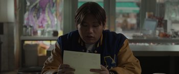 Movie still from “Spider-Man: No Way Home” (2021), directed by Jon Watts – A person sitting at a table looking at a piece of paper; Close Up shot, Low angle