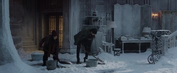 Movie still from “Spider-Man: No Way Home” (2021), directed by Jon Watts – A man shoveling snow into a bucket while another man looks on; Wide shot, High angle
