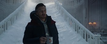 Movie still from “Spider-Man: No Way Home” (2021), directed by Jon Watts – A man holding a cup in his hand while standing in the snow; Medium shot, High angle