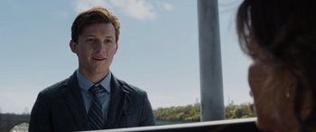 Movie still from “Spider-Man: No Way Home” (2021), directed by Jon Watts – A man in a suit and tie standing next to a pole; Close Up shot, Over the shoulder angle