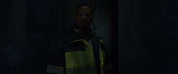 Movie still from “Spider-Man: No Way Home” (2021), directed by Jon Watts – A man in a yellow and black jacket standing next to a wall; Medium shot, High angle