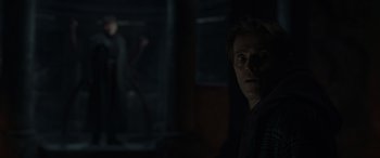 Movie still from “Spider-Man: No Way Home” (2021), directed by Jon Watts – A man standing in a dark room looking at the camera; Medium shot, Over the shoulder angle