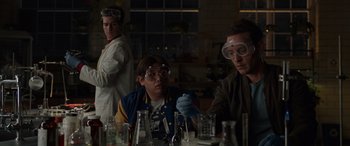 Movie still from “Spider-Man: No Way Home” (2021), directed by Jon Watts – A group of people in a room working with lab glassware; Medium shot, Over the shoulder angle
