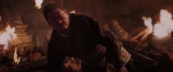 Movie still from “Spider-Man: No Way Home” (2021), directed by Jon Watts – A man with a bandaged head and face is standing in a dark room; Medium shot, Low angle