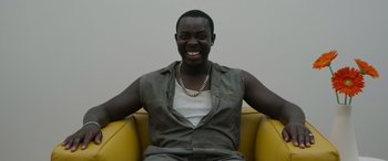 Movie still from “Spiderhead” (2022), directed by Joseph Kosinski – A man sitting in a chair with his hands on his chest; Medium shot, Low angle