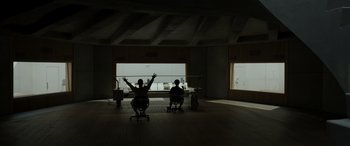 Movie still from “Spiderhead” (2022), directed by Joseph Kosinski – Two people sitting at a table in a room; Extreme Wide shot, Low angle