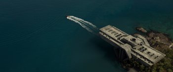 Movie still from “Spiderhead” (2022), directed by Joseph Kosinski – An aerial view of a jet boat going over a bridge; Extreme Wide shot, Overhead angle