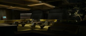 Movie still from “Spiderhead” (2022), directed by Joseph Kosinski – A group of tables and benches in a room; Extreme Wide shot, High angle