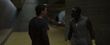Movie still from “Spiderhead” (2022), directed by Joseph Kosinski – Two men are standing in a hallway talking; Medium shot, Over the shoulder angle
