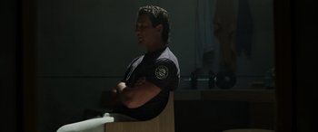 Movie still from “Spiderhead” (2022), directed by Joseph Kosinski – A man sitting in a chair with his arms crossed; Medium shot, Over the shoulder angle