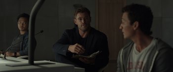 Movie still from “Spiderhead” (2022), directed by Joseph Kosinski – A man sitting in front of another man holding a piece of paper; Medium shot, Over the shoulder angle