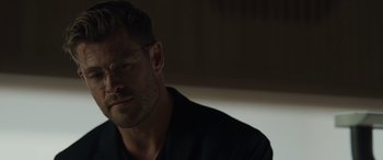 Movie still from “Spiderhead” (2022), directed by Joseph Kosinski – A person wearing glasses and a black shirt; Close Up shot, Over the shoulder angle